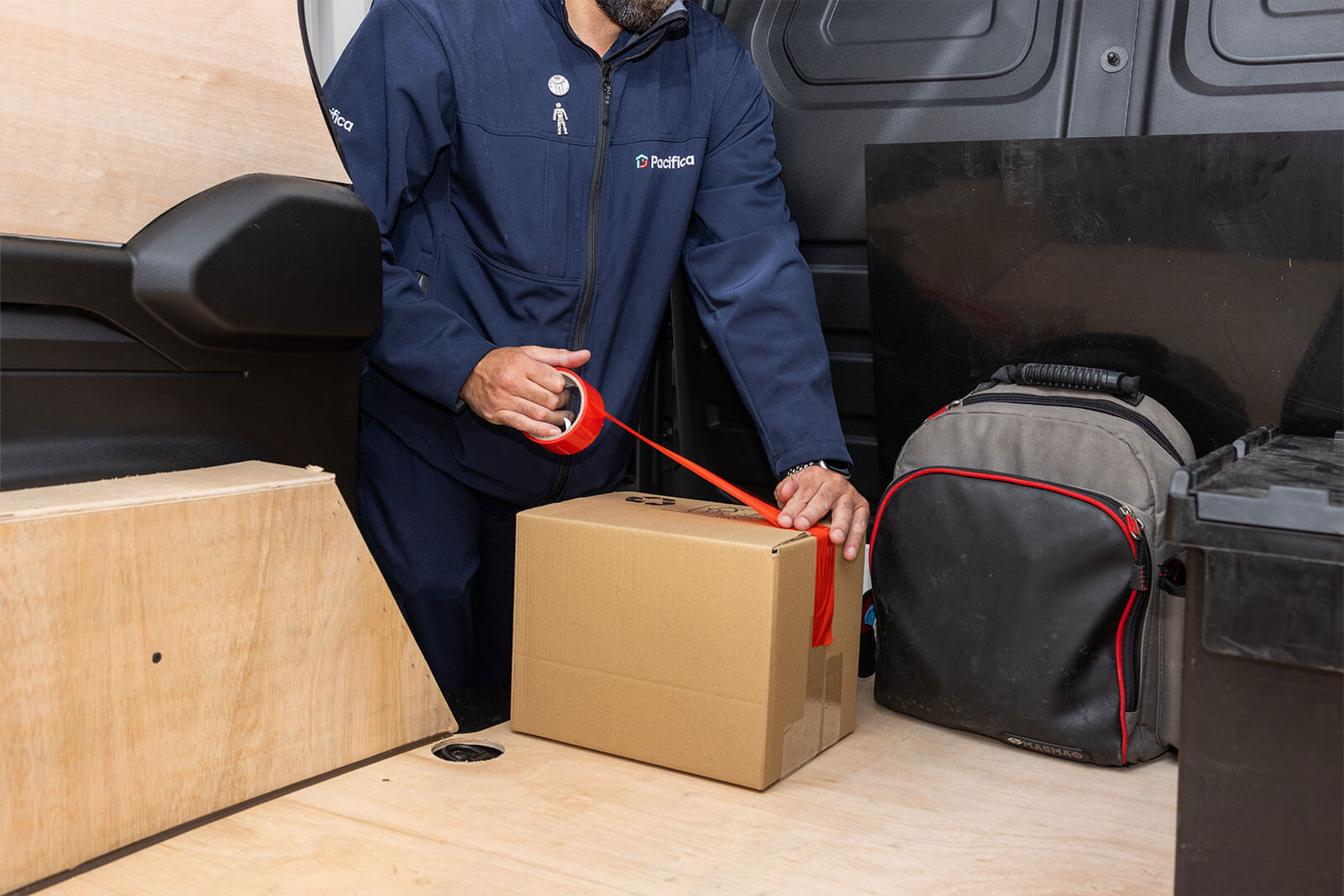 Pacifica engineer packing a cardboard box in back of van