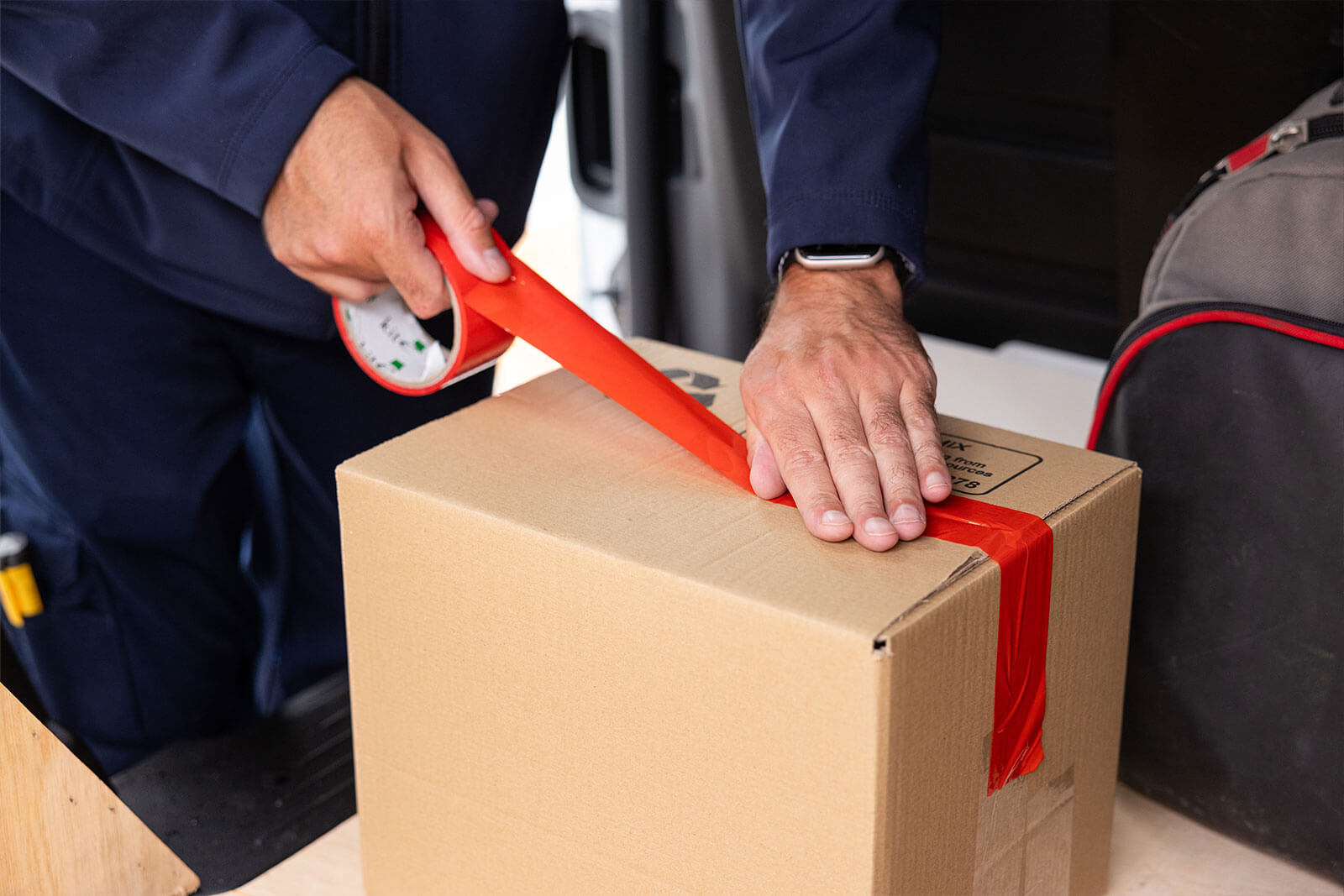 close-up of Pacifica engineer packaging up a box with red tape