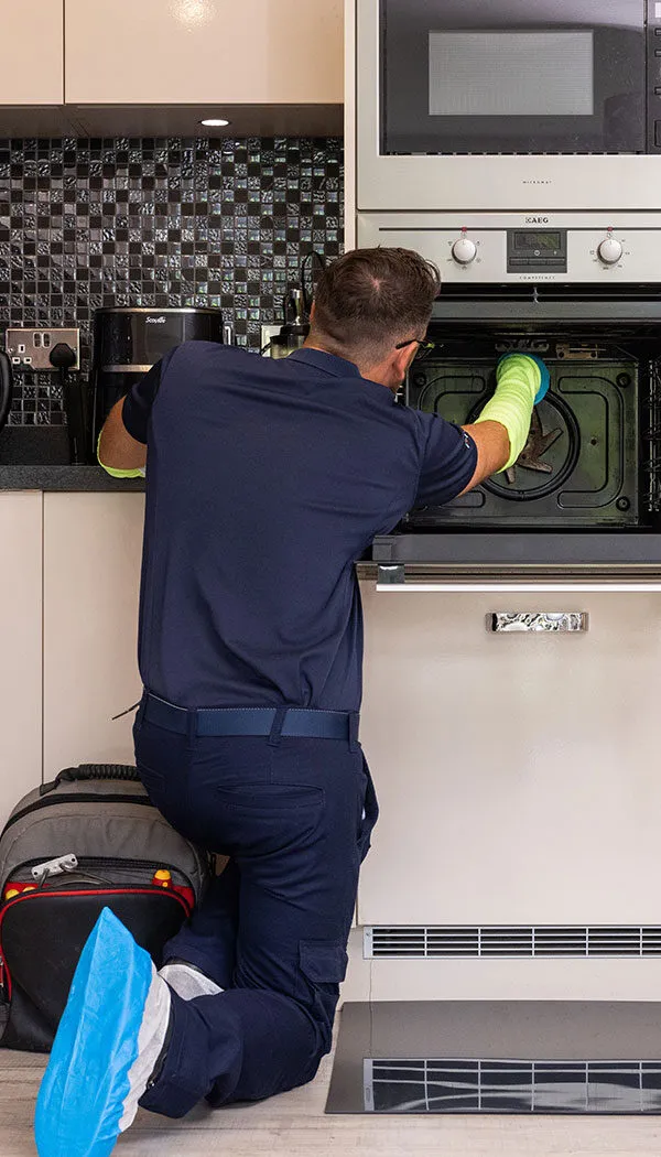 Pacifica engineer kneeling down to fix oven fan issue